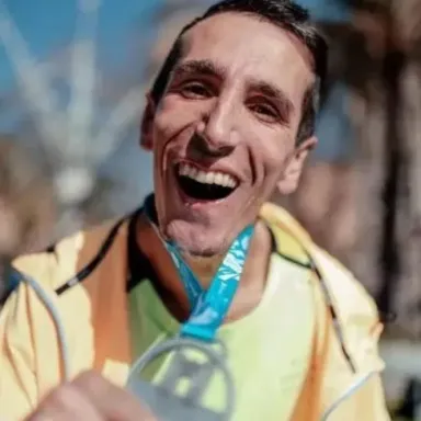 Álex Roca, atleta con parálisis cerebral, sonriendo con su medalla de maratón