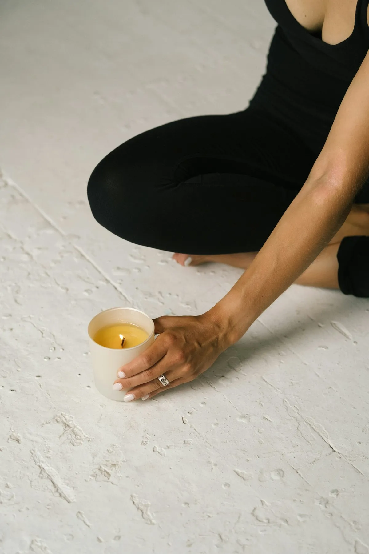 Mujer sentada en el piso encendiendo una vela, en un momento de pausa y cuidado personal