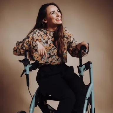 Miriam Fernández, cantante con parálisis cerebral, sonriendo sentada en su andadera